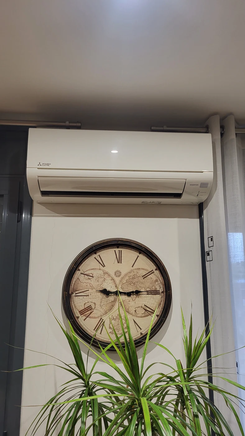 Aire condicionat Mitsubishi Electric instal·lat sobre un rellotge de paret gran