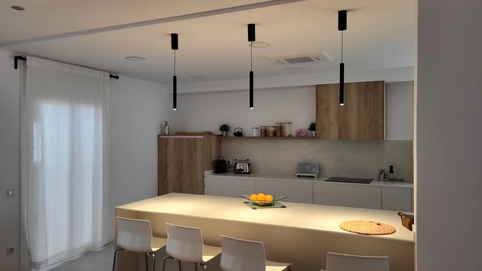 Cuina amb illa, llums penjants i climatització de cassette integrada al sostre, una feina de Garrido Serveis